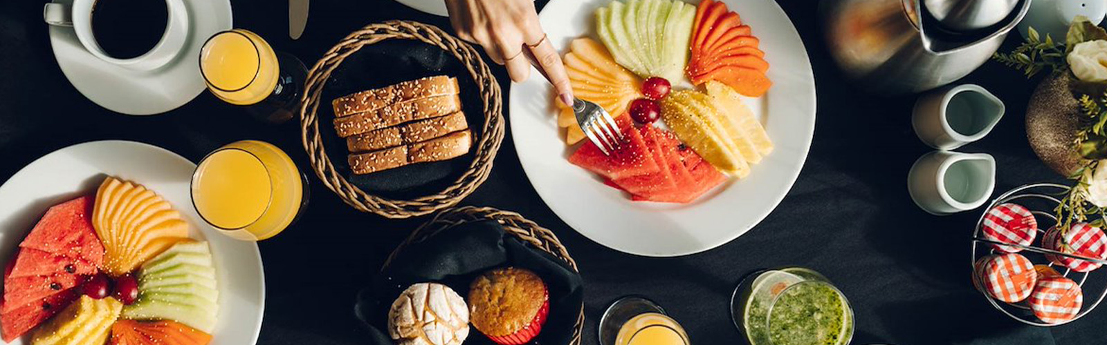 a plate of fruit and a hand holding a fork