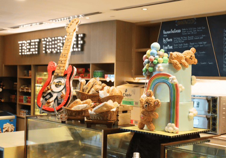 a display case with a guitar and a rainbow cake and teddy bears