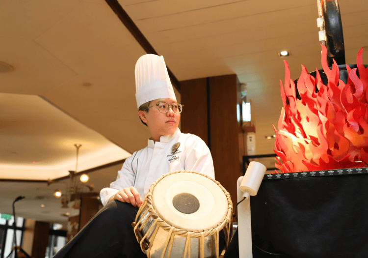 a man in a chefs hat and glasses sitting next to a drum