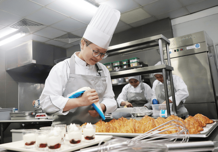 a man in a chefs hat and aprons in a kitchen