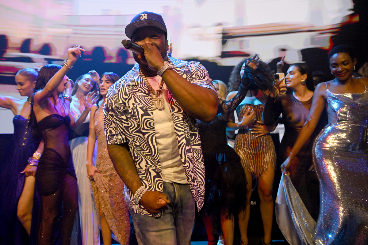 a man singing into a microphone with a crowd of people around him